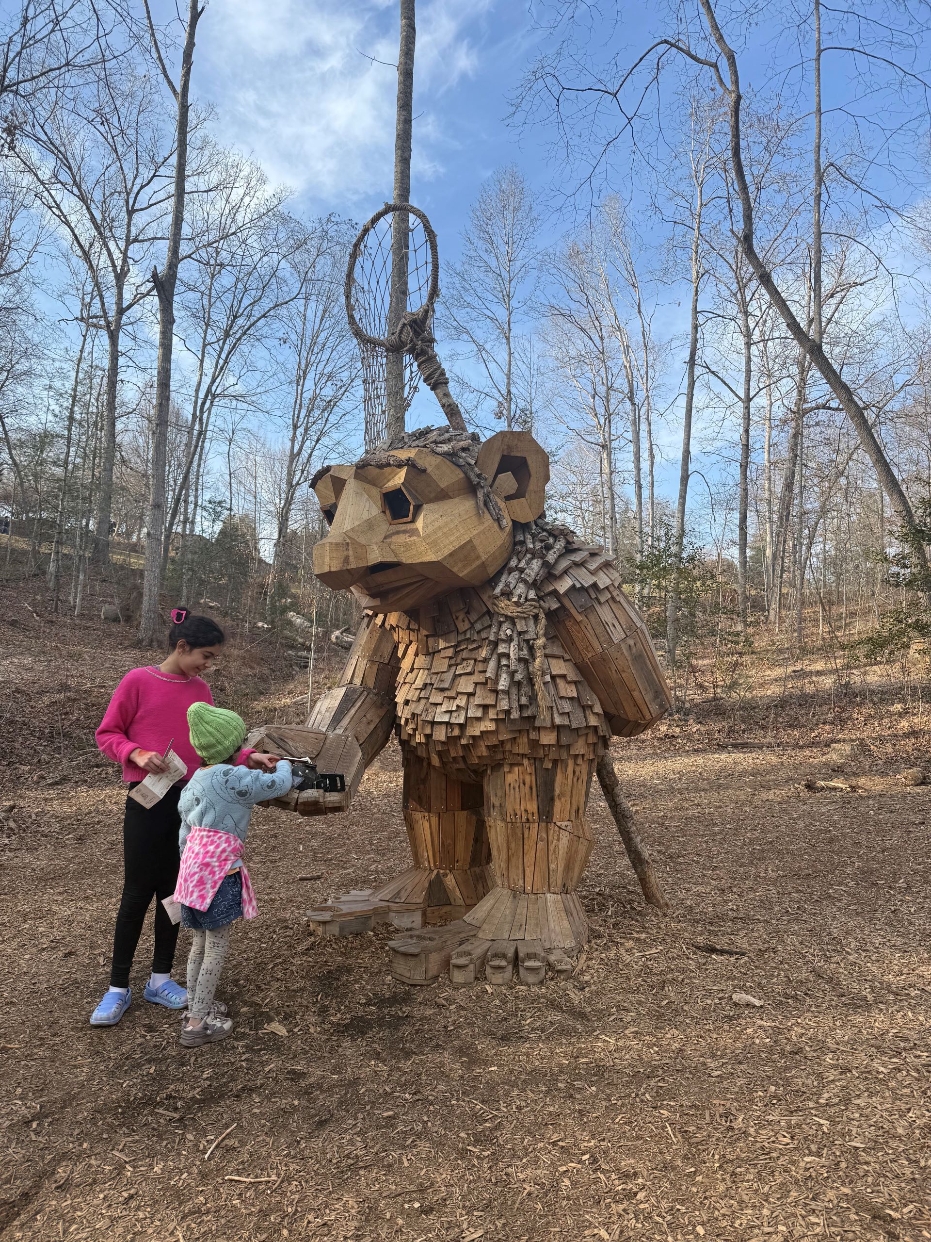Larger than lifesize troll with two girls standing in front of it